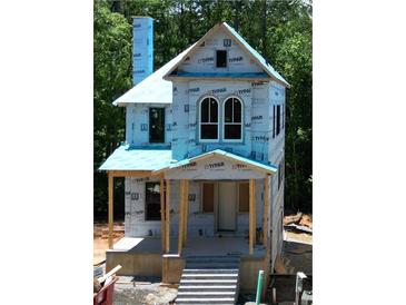 Two-story house under construction with a covered porch and windows ready for installation at 11825 Serenbe Ln, Chattahoochee Hills, GA 30268