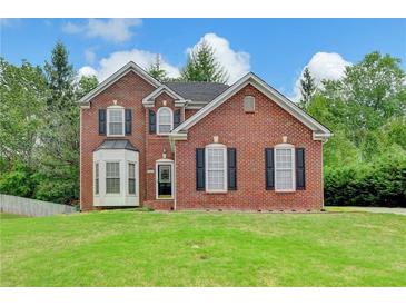 Charming two-story brick home featuring a well-manicured lawn, black shutters and a beautiful bay window at 2455 Kirkstone Dr, Buford, GA 30519