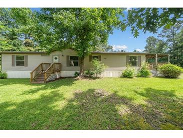 Charming single-story home with a well-maintained lawn, inviting entryway, and a large mature tree providing ample shade at 170 White Rose Ln, Temple, GA 30179