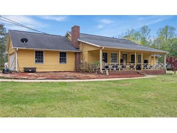 Inviting yellow home with a covered porch, lush lawn, and mature trees at 255 Deer Run Rd, Ellenwood, GA 30294