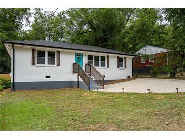 Charming, updated single-story home featuring a blue door, white painted brick, and a well-maintained front yard at 831 Catherine St, Forest Park, GA 30297