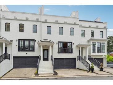 Charming white brick townhome featuring a black garage and a welcoming front entrance with staircase at 3667 Peachtree Ne Rd # 6, Atlanta, GA 30319