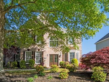 Inviting brick home featuring a meticulously landscaped front yard with lush greenery and mature trees at 630 Bluff Oak Ct, Roswell, GA 30076