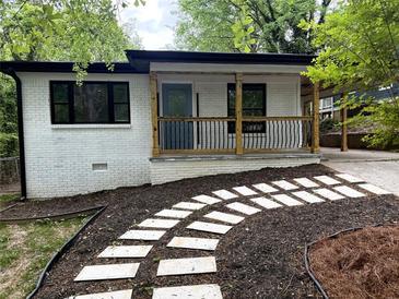 Charming home with a white painted brick, covered front porch and a stone walkway through the landscaped front yard at 875 Hall Nw St, Atlanta, GA 30318