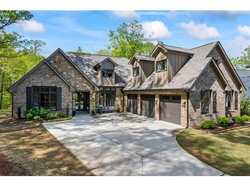 Beautiful home featuring stone and brickwork with a three-car garage and large driveway at 1188 Woodtrace Ln, Auburn, GA 30011