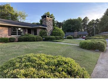 Charming brick home with a stone chimney and well-manicured landscaping in a suburban neighborhood at 3358 Stonecrest Ct, Atlanta, GA 30341