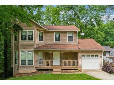 Charming two-story home with a cozy front porch and attached garage, nestled among lush greenery at 706 Cather Ct, Stone Mountain, GA 30088
