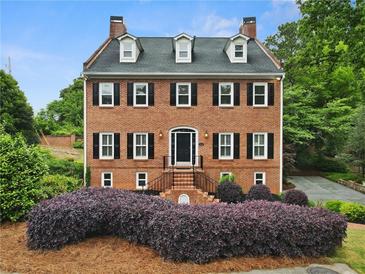 Elegant brick two-story home featuring symmetrical windows, black shutters, and manicured landscaping at 100 Barnard Pl, Atlanta, GA 30328