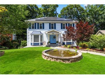 Charming two-story home with a well-manicured lawn, blue accents, and a decorative front pond at 4909 Glenwhite Dr, Duluth, GA 30096