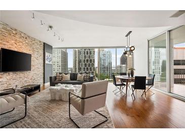 Inviting living room with a decorative stone wall, hardwood floors, and a stunning city view through expansive windows at 20 10Th Nw St # 2003, Atlanta, GA 30309