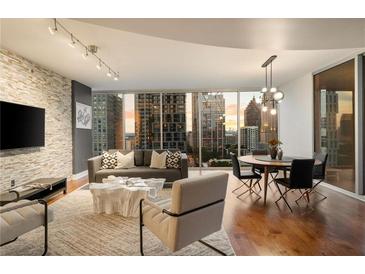 Bright living room featuring a stone accent wall, hardwood floors and expansive windows showcasing city views at 20 10Th Nw St # 2003, Atlanta, GA 30309