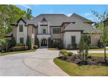 Elegant brick and stucco home featuring a circular driveway and manicured landscaping at 140 Johnson Rd, Suwanee, GA 30024