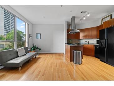 Open living room featuring hardwood floors, large windows and a modern kitchen with stainless steel appliances at 2626 Peachtree Nw Rd # 606, Atlanta, GA 30305