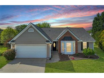 Charming single-story home showcasing a landscaped front yard, bay window, and two-car garage with a beautiful sunset in the background at 2602 Midler Ct, Buford, GA 30519
