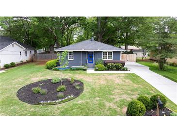 Charming single story home with landscaped front yard, featuring a blue front door and a long driveway at 957 Sharon Se Cir, Smyrna, GA 30080