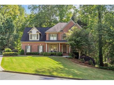 Charming brick home with well-manicured lawn and mature trees providing ample shade at 1880 Barrett Dr, Cumming, GA 30040