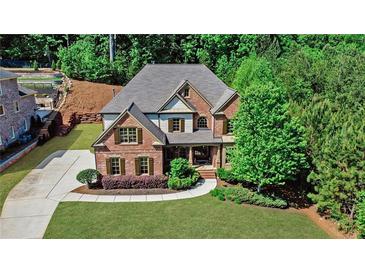 Charming brick home featuring a well-manicured lawn, mature trees, and a long driveway at 1168 Woodtrace Ln, Auburn, GA 30011