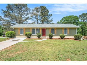 Charming one-story home with a well-manicured lawn, shutters and a welcoming red front door at 898 Doeskin Nw Dr, Conyers, GA 30012