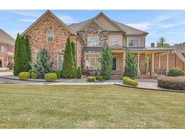 Charming two-story brick home with stone accents, manicured lawn, and covered front porch at 2932 Springbluff Ln, Buford, GA 30519