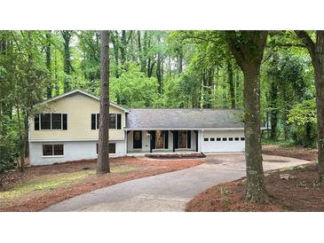 Charming exterior view of home featuring a welcoming facade and attached garage amid a lush, green wooded lot at 4639 Hardwood Rd, Stone Mountain, GA 30083