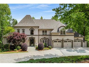 Stately home featuring manicured landscaping, stone driveway, and a three-car garage, exuding curb appeal at 8345 Jett Ferry Rd, Sandy Springs, GA 30350