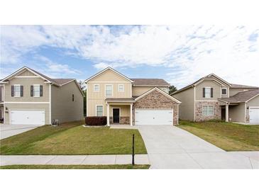 Inviting two-story home featuring a well-manicured lawn and attached two-car garage at 7747 Rudder Cir, Fairburn, GA 30213