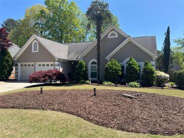 Charming home featuring manicured front lawn, mature landscaping, and an attached two-car garage at 2435 Jakin Way, Suwanee, GA 30024