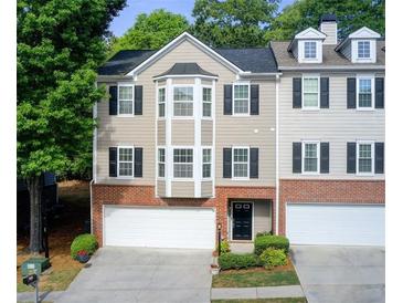 Charming townhome featuring a brick facade, black shutters, and attached two-car garage at 376 Eagle Tiff Dr, Sugar Hill, GA 30518