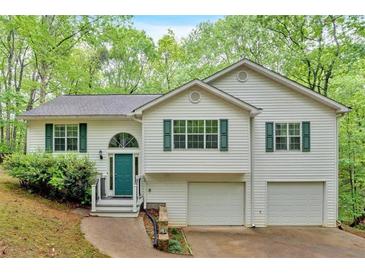 Charming two-story home with white siding, green shutters, and a two-car garage nestled amongst lush trees at 2539 Lakeside Dr, Villa Rica, GA 30180