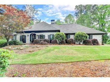 Beautiful one-story home with a manicured lawn and mature trees, showcasing its curb appeal at 5475 Trowbridge Dr, Dunwoody, GA 30338