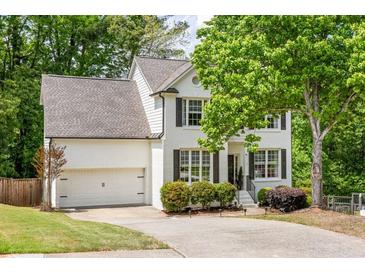 Charming two-story home with a white brick exterior, well-manicured landscaping, and attached two-car garage at 6000 Hampton Bluff Way, Roswell, GA 30075