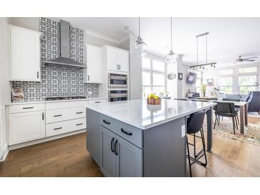 Bright open kitchen features white cabinets, gray island, stainless appliances and decorative backsplash at 834 S Columbia Dr, Decatur, GA 30030