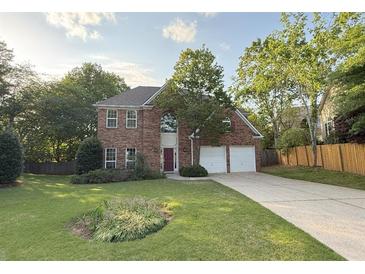 Charming brick two-story home with well-manicured lawn and a long driveway leading to a two-car garage at 310 Bloomfield Ct, Roswell, GA 30075