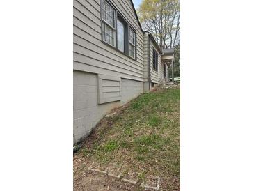 Home exterior featuring neutral siding, basement with vents, and double-hung windows with dark trim at 4064 Sunset Dr, Atlanta, GA 30331