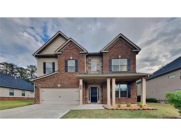Charming brick two-story home boasts a covered porch, two-car garage, and manicured lawn at 245 Brickstone Pkwy, Covington, GA 30016