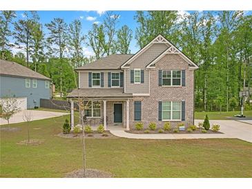 Charming two-story home with a brick facade, covered porch, manicured lawn and tree lined backdrop at 571 Hancock Se Dr, Atlanta, GA 30354