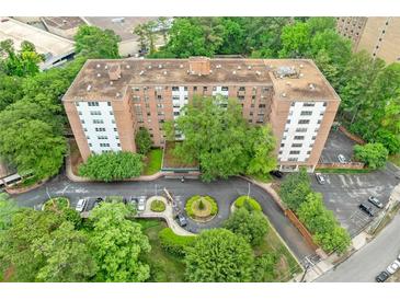 An aerial view of a brick apartment building surrounded by lush greenery and ample parking at 2965 Pharr Court South Nw # 718, Atlanta, GA 30305