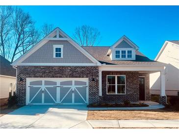 Charming brick home featuring a two-car garage and a welcoming covered porch, perfect for suburban living at 7220 Winderlea Ln, Cumming, GA 30040