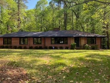 Ranch-style brick home with mature trees and landscaping creating a serene and private setting at 3080 Hogan Sw Rd, Atlanta, GA 30331