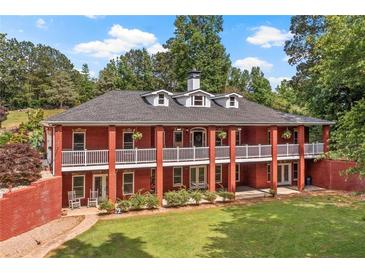Sprawling brick home featuring a double porch, manicured lawn, and mature trees for an inviting curb appeal at 7180 Westray Rd, Cumming, GA 30028
