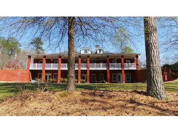 Expansive brick home featuring a wide porch, white railing, and large columns at 7180 Westray Rd, Cumming, GA 30028