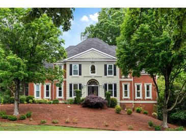 Stately brick home featuring classic architecture, arched entry, dark shutters, and mature landscaping at 790 Thornberry Dr, Alpharetta, GA 30022
