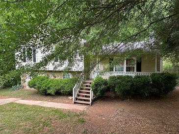 Charming home featuring a covered porch with lush landscaping surrounding the property at 2756 Del Ridge Dr, Douglasville, GA 30135