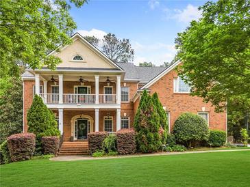 Beautiful two-story brick home with a welcoming front porch and manicured landscaping at 940 Kinghorn Nw Dr, Kennesaw, GA 30152