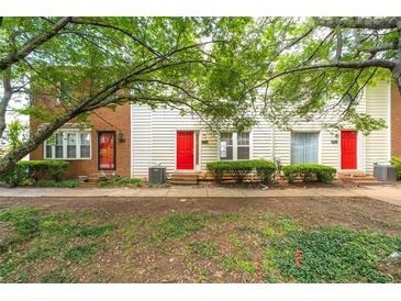 Exterior view of townhomes featuring colorful doors, tidy landscaping, and a lush green space in front at 238 Chads Ford Way, Roswell, GA 30076
