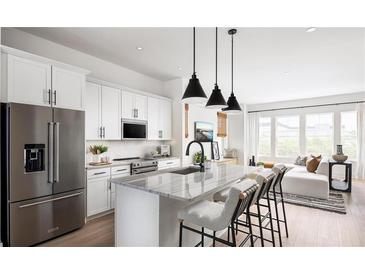 Modern kitchen with white cabinets, stainless steel appliances, and a marble countertop island with pendant lighting at 506 Motivation Nw Cir, Atlanta, GA 30309