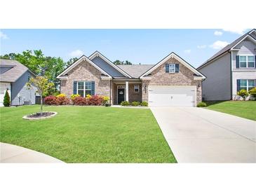Charming brick home with lush green lawn, manicured landscaping, and a two-car garage at 3322 Grace Farm Ln, Buford, GA 30519