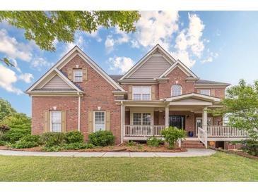 Charming two-story brick home with a welcoming front porch and beautifully landscaped front yard at 1032 Jordan Rd, Dacula, GA 30019