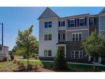 Charming townhome showcasing a blend of white and brick facade, complemented by landscaped front yard at 1899 Deco Dr, Kennesaw, GA 30144