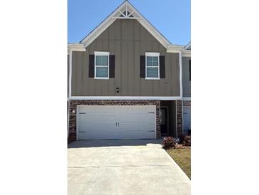 Two-story townhome with a large two car garage, neutral siding and black shutters at 11692 Mendenhall Ct, Hampton, GA 30228